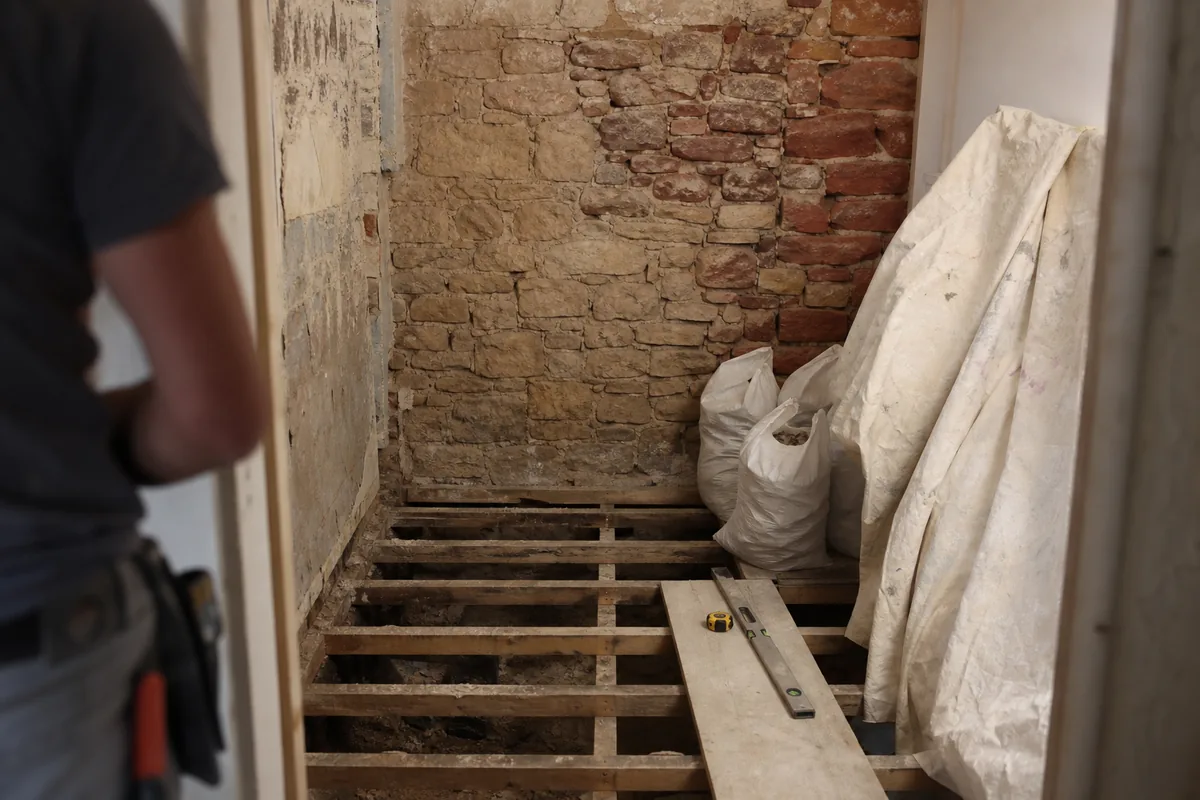 Salle d&rsquo;eau étroite en cours de rénovation dans une maison de ville de Rodez, mur de grès rouge apparent