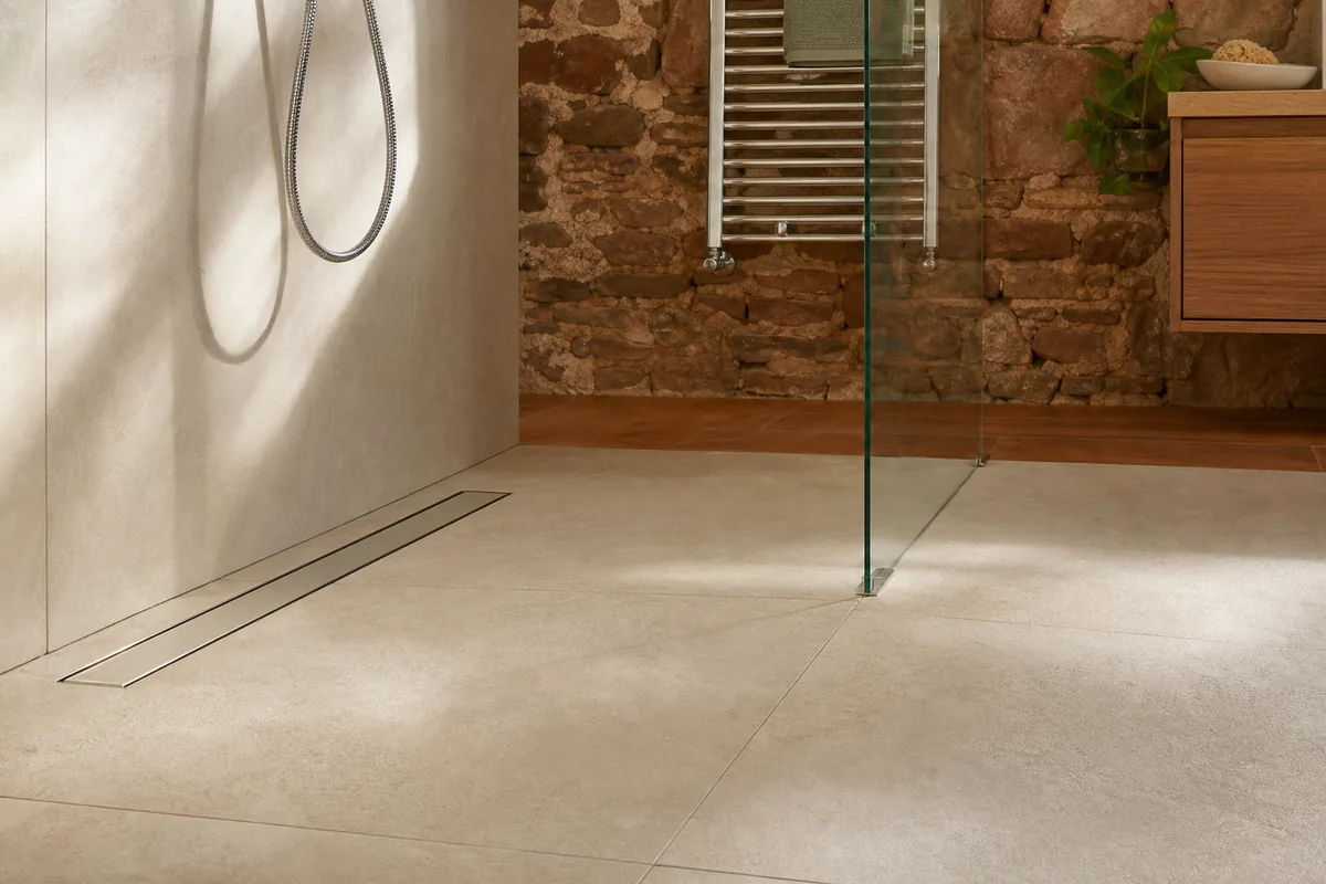 Douche à l’italienne carrelée grand format dans une maison de plateau, lumière naturelle rasante sur le receveur